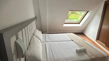Un dormitorio con tragaluces, una cama, una mesita de noche y suelo de madera.