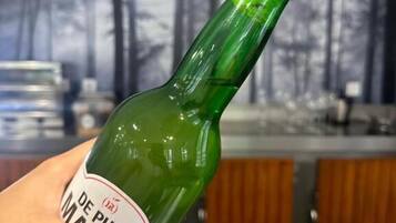 Eine Hand hält eine grüne Flasche mit dem Aufdruck 'DE PURA MARE'.
