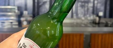 A hand holding a green bottle with a label that reads "DE PURA MARE."