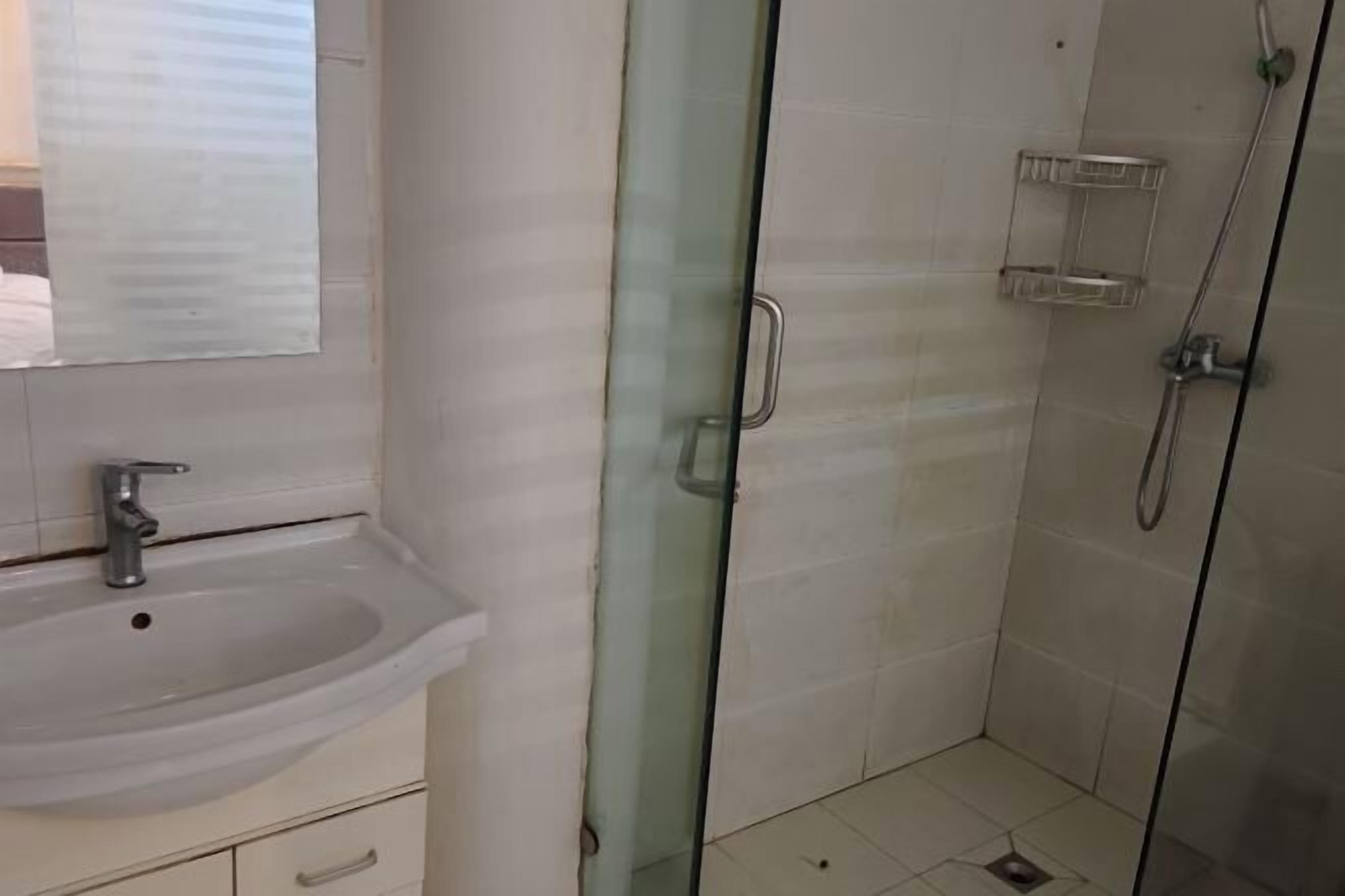 A bathroom with a sink, mirror, and glass shower enclosure.