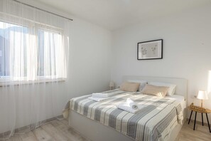 Un llit ben arrenjat amb un estovat a ratlles, un quadre al mur i una làmpada de nit.