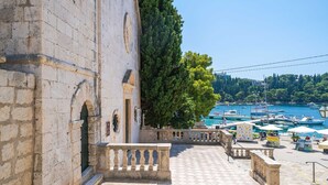 A stone building with a balcony overlooking a marina with boats.