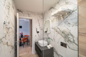 A modern bathroom with marble walls, a round sink, and a towel rack.