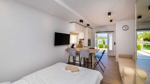 A modern hotel room with a bed, a desk with chairs, a TV, and a view of the outdoors.