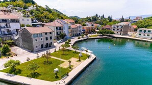 A waterfront property with a paved walkway, a grassy area, and buildings with balconies.