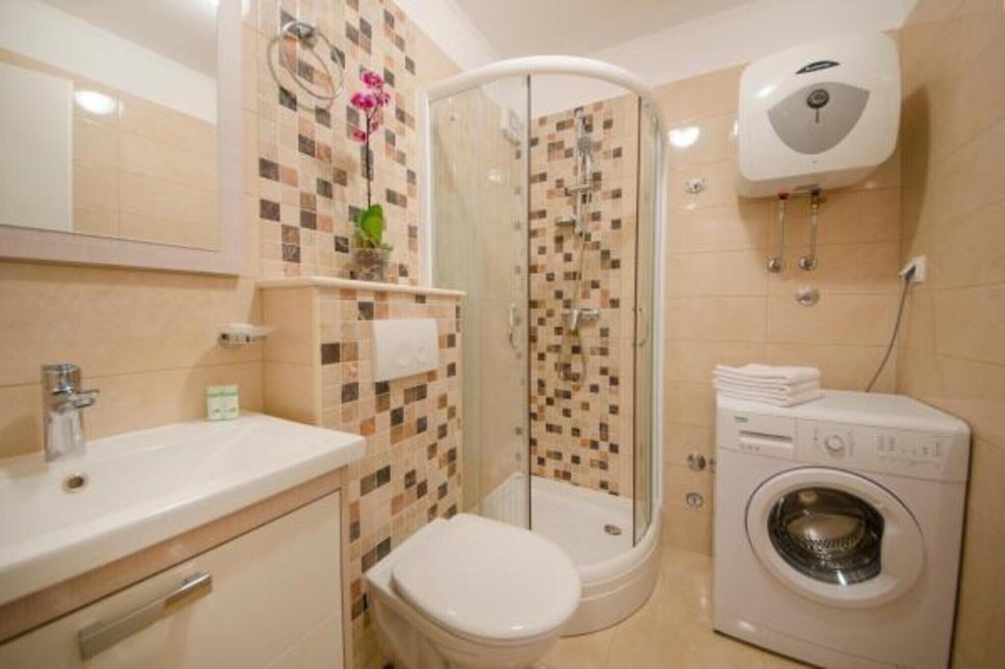 Ein Badezimmer mit Dusche, Toilette, Waschbecken und Waschmaschine.