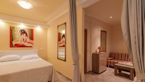 Ein Hotelzimmer mit Bett, einer Couch, einem kleinen Tisch, einem Spiegel und einem Gemälde an der Wand.