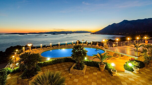 Ein Poolbereich mit Blick auf das Meer und die Berge im Abenddämmerung.