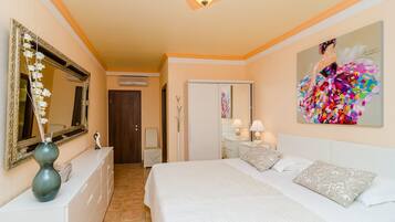 Ein Hotelzimmer mit einem großen Bett, einem Schminktisch, einem Spiegel, einem Gemälde und einer Vase mit Blumen.