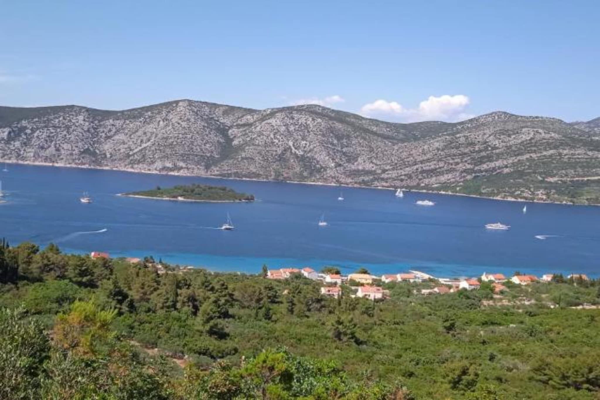 A coastal view with boats, a small island, and a town with red-roofed buildings.