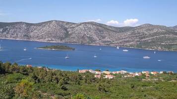 A coastal view with boats, a small island, and a town with red-roofed buildings.