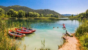 Un fiume tranquillo con kayak e una persona che salta in acqua.
