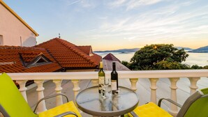 A balcony with a table, chairs, and a bottle of wine.