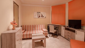 Un espacio habitable compacto con un sofá, una mesa de comedor, un televisor y un armario.