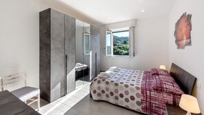 A bedroom with a bed, a desk, a chair, a wardrobe, a bathroom, and a view of the outdoors. - Apartment 'Cà Teodoi' with Sea View, Wi-Fi and Air Conditioning (Genova)