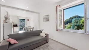 A modern living room with a sofa, a rug, and a dining area in the background. - Apartment 'Cà Teodoi' with Sea View, Wi-Fi and Air Conditioning (Genova)