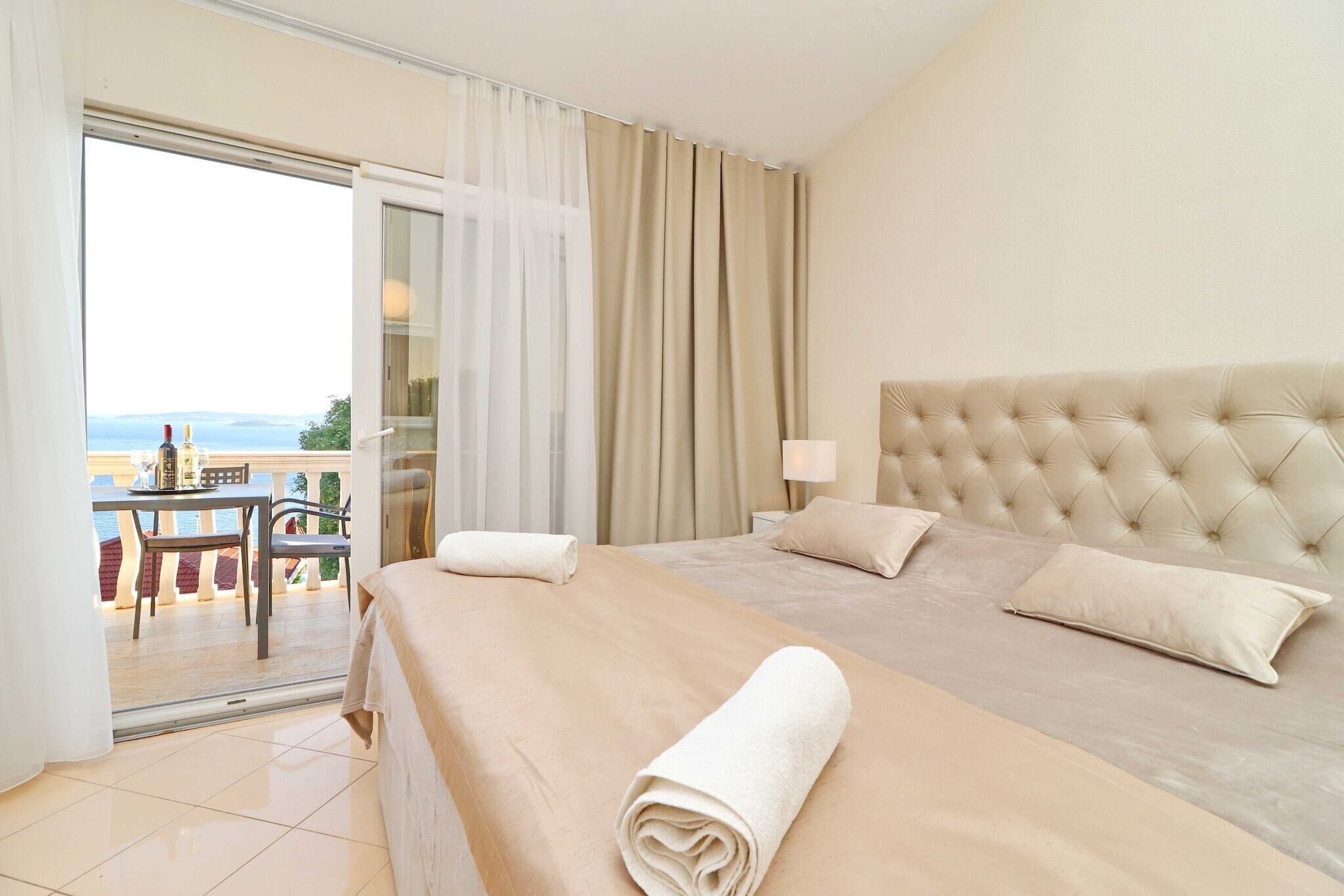 Habitación de hotel con una cama grande, un balcón con mesa y sillas, y vistas al mar.
