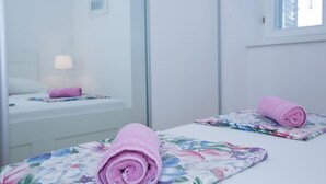 Ein Hotelzimmer mit einem Bett, einem Nachttisch mit Lampe und einem Spiegel, der den Raum reflektiert.