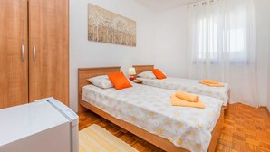 Un dormitorio con dos camas, un armario de madera y un cuadro en la pared.