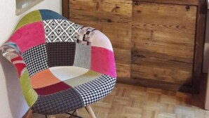 A room with a wooden ceiling, a wooden cabinet, a colorful chair, and a red toolbox. - Apartment 'Mansarda Le Chateau' with Mountain View, Shared Garden and Wi-Fi (Aymavilles)