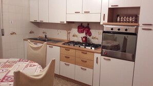 A kitchen with white cabinets, a stove, an oven, and a sink. - Apartment 'Mansarda Le Chateau' with Mountain View, Shared Garden and Wi-Fi (Aymavilles)