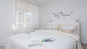 Cama bem arrumada com lençóis brancos e almofadas decorativas.
