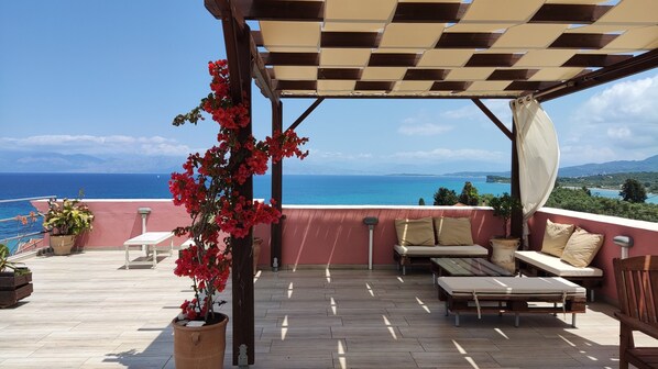 A covered outdoor seating area with a view of the sea, a pergola, and potted plants. - Studio Apartment 'GRAND  4' with Sea View, Wi-Fi and Air Conditioning (Corfu)