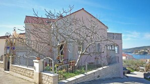 A two-story house with a red-tiled roof, a white exterior, and a stone wall. - Apartments Villa Rose - Economy Studio with Sea View and shared  Terrace (A3 crveni) (Sumartin)