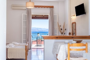 Une chambre d’hôtel avec un balcon, une télévision, une table avec un bol et une chaise.