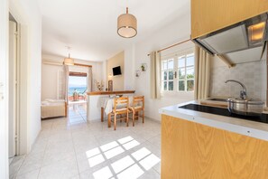 Une cuisine moderne dotée d’une grande fenêtre, un coin repas avec une table et des chaises, et une vue sur la mer.