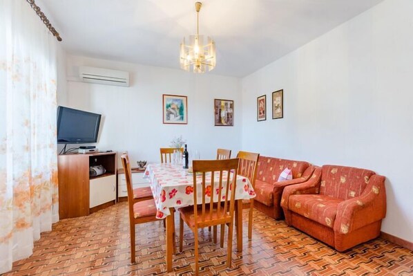 Un comedor con una mesa, sillas, un sofá y un televisor.