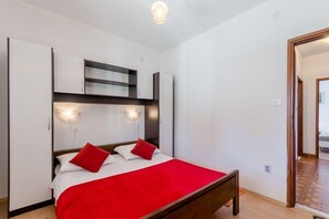 A bedroom with a bed, a wardrobe, and a built-in shelf unit.