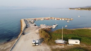 Vue aérienne d’une marina avec des bateaux amarrés, un petit bâtiment et une route menant à la marina.