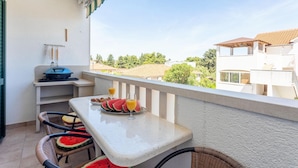 Ein Balkon mit Frühstückstisch, mit Wassermelonenstücken und Orangensaft, mit Blick auf eine Wohngegend.