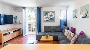 Ein Wohnzimmer mit einer Couch, einem Couchtisch, einem Fernseher und Kunstwerken an den Wänden.