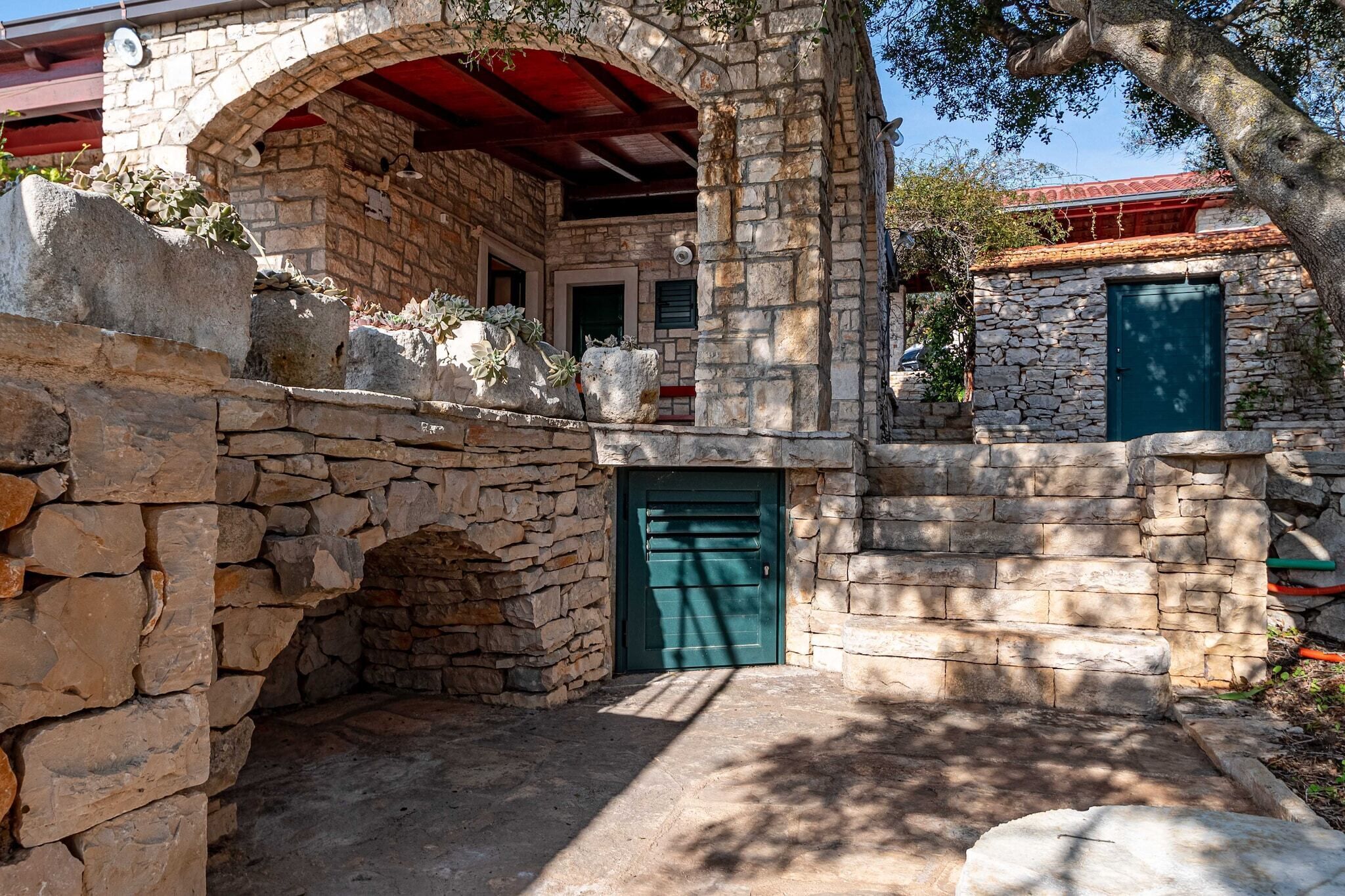 Un bâtiment en pierre avec une porte verte, un arc en pierre et un toit rouge.