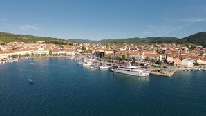 A coastal town with a marina, buildings, and hills in the background.