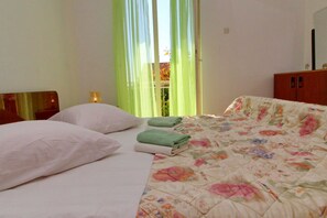Relax in a cozy space with a neatly made bed, wooden headboard, and a balcony offering a view.