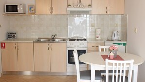 A kitchen with a microwave, stove, sink, and a table with chairs.
