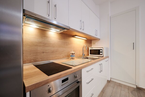A modern kitchen with white cabinets, a stainless steel range, a microwave, and a wooden countertop. - Apartment Boris (ST) - Two Bedroom Apartment with Terrace and Jacuzzi (Trogir)