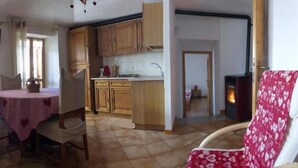 Un comedor con mesa y sillas, una cocina con armarios de madera y una chimenea.