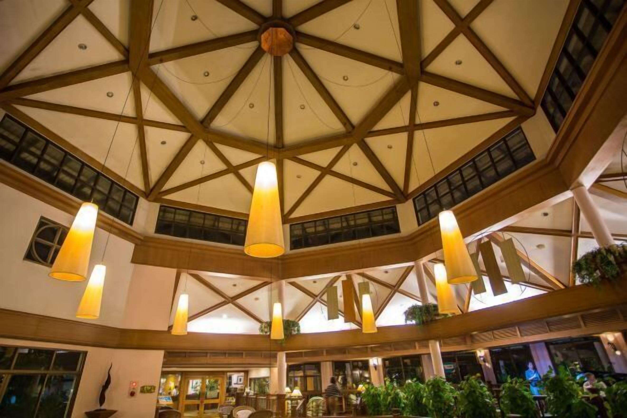 Un vaste atrium doté d’un haut plafond, de poutres en bois et de luminaires suspendus.