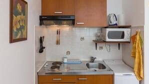 Une cuisine compacte dotée de meubles en bois, d’un four à micro-ondes, d’une bouilloire et d’un évier.