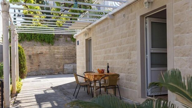 Un espace extérieur aménagé avec une table et des chaises, une pergola et un mur en pierre.