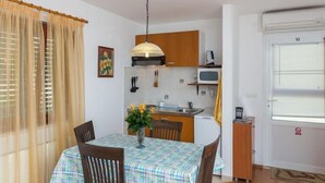 Une cuisine compacte dotée de meubles en bois, d’un four à micro-ondes et d’un coin repas avec une table dressée pour deux personnes.