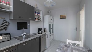 Una cocina compacta con gabinetes grises, un lavamanos, una cafetera y un refrigerador.