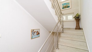 A staircase with a metal railing, white walls, and a framed picture of puppies.