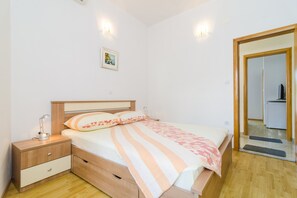 A bedroom with a bed, bedside table, lamp, and a framed picture on the wall. - Apartments & Rooms Barišić - Double Room with Balcony and City View(First Floor)(Soba 11) (Kupari)