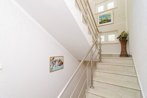 Una escalera con barandilla, una planta en maceta y dos cuadros en la pared.