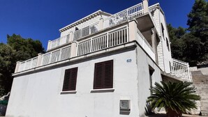 Ein weißes Gebäude mit Balkon, der Hausnummer '623' an der Wand und einem Blumentopf.
